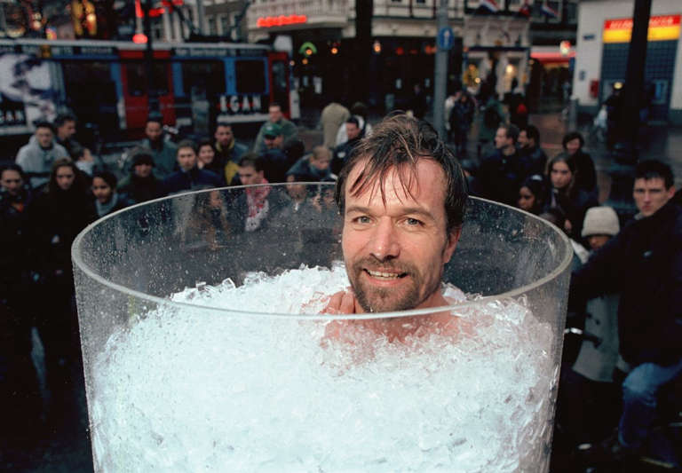 Wim Hof "Iceman" baignant dans un bain de glace qui sourit à la personne qui le prend en photo.