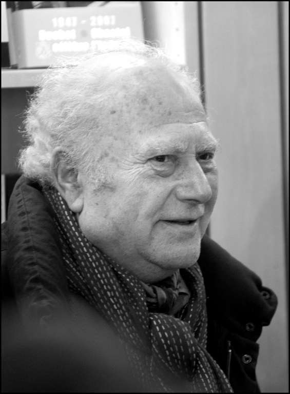 Portrait en noir et blanc de Michel Polac âgé, souriant, une écharpe tissée autour du cou