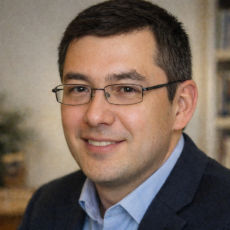 Teddy Basile, fondateur de Psytheos en photo portant des lunettes de vues, habillé en costume noir avec une chemise bleue.